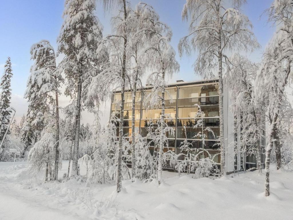a building covered in snow next to trees at Holiday Home Tievan aurinkorinne dina by Interhome in Sirkka
