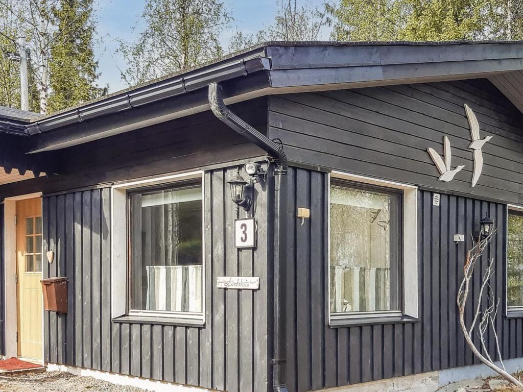 ein schwarzes Haus mit einer Tür und einem Fenster in der Unterkunft Holiday Home Mustalampi 3 lintukoto by Interhome in Niskala