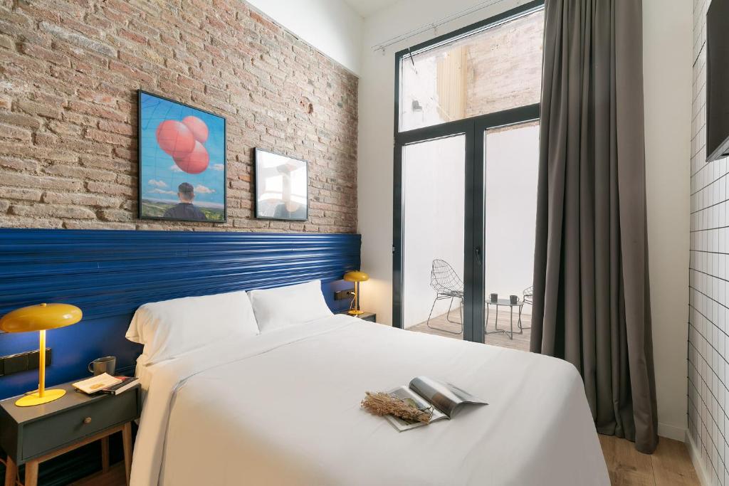 a bedroom with a white bed and a brick wall at Arte Suites by Olala Homes in Hospitalet de Llobregat