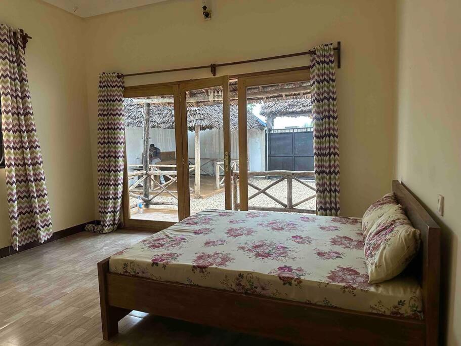 um quarto com uma cama e uma porta de vidro deslizante em Bhome Zanzibar em Kiwengwa