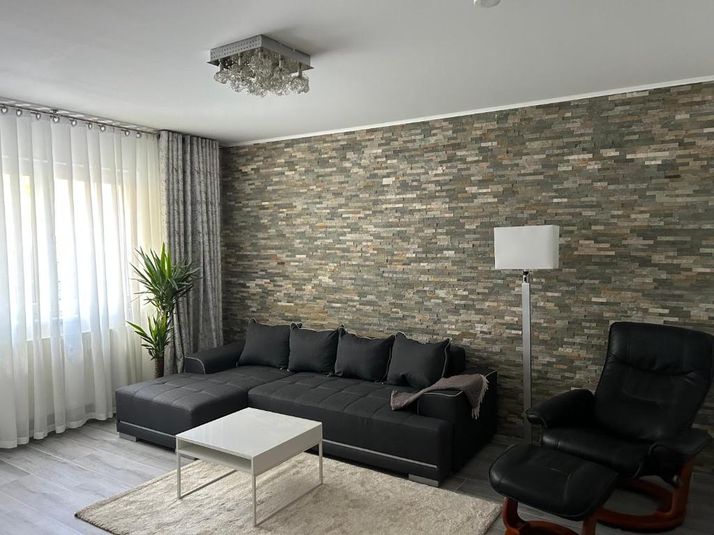 ein Wohnzimmer mit einem schwarzen Sofa und einer Ziegelwand in der Unterkunft Apartment Hamburg Perle in Hamburg