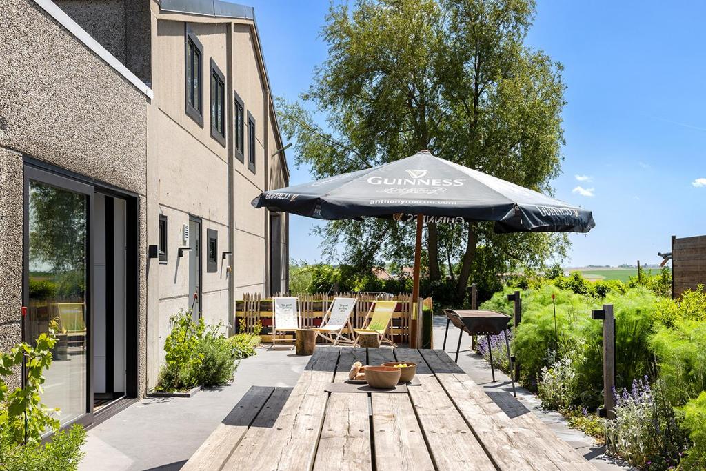 a patio with an umbrella and chairs and a table at Vakantieverblijf De Backstage in Heuvelland