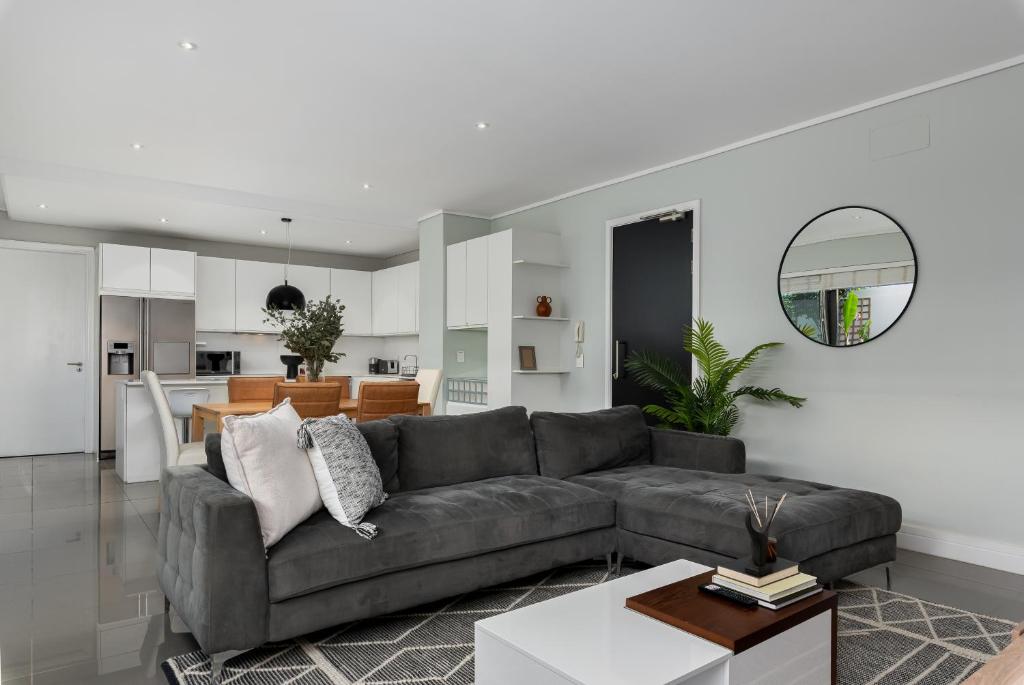 uma sala de estar com um sofá cinzento e uma cozinha em The Richmond G02 em Cidade do Cabo