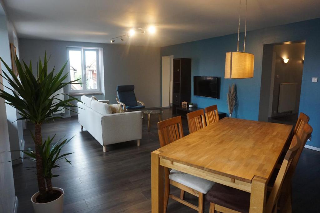 a dining room and living room with a table and a couch at L'Aubach - appartement spacieux in Scherwiller