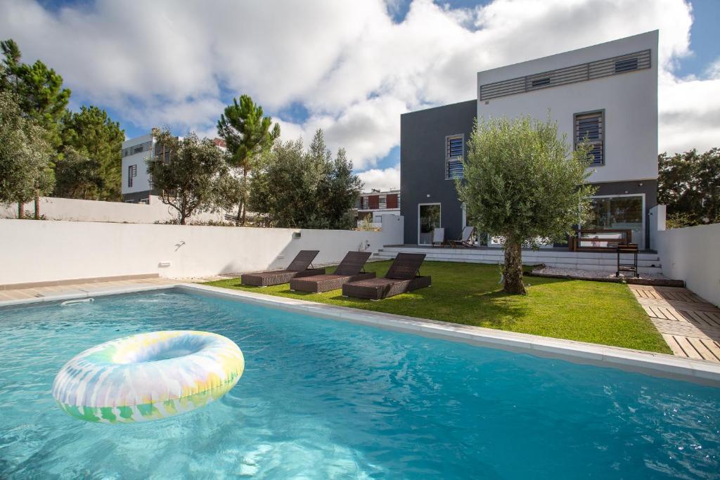 uma casa com uma piscina com um flutuador na água em Alto das Vinhas Lovers - Sesimbra em Sesimbra