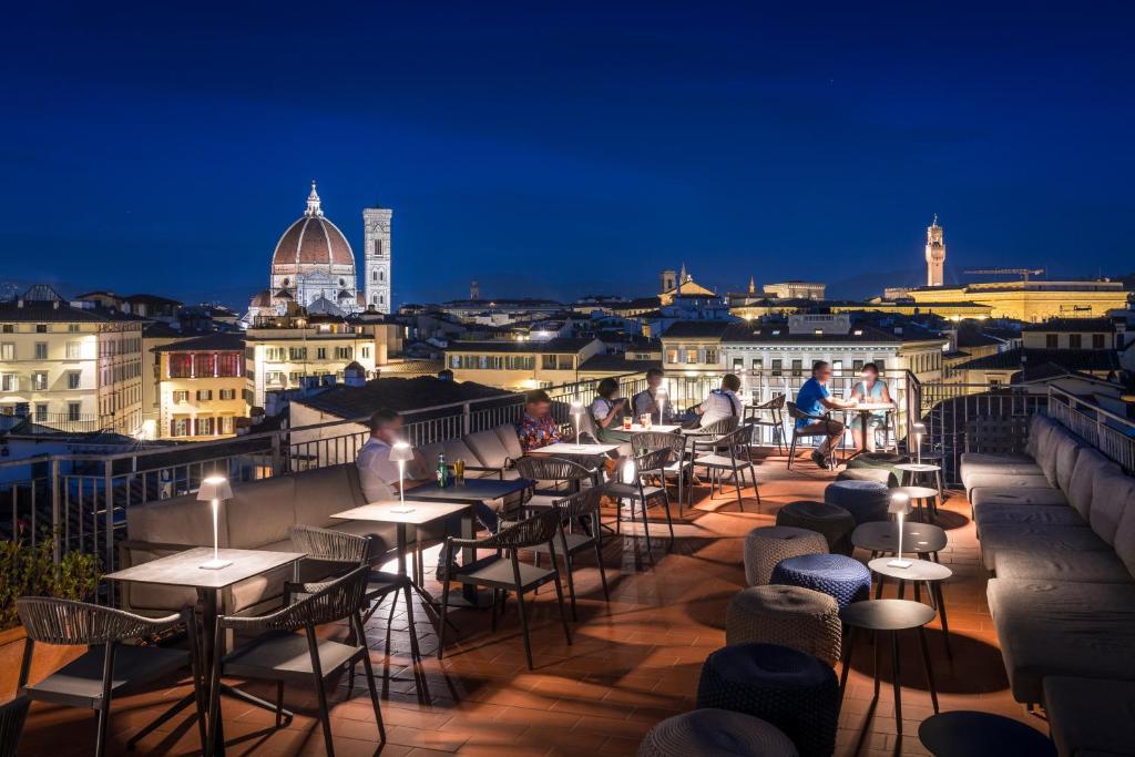フィレンツェにあるホテル クローチェ ディ マルタの夜間のバルコニーにテーブルと椅子が並ぶ