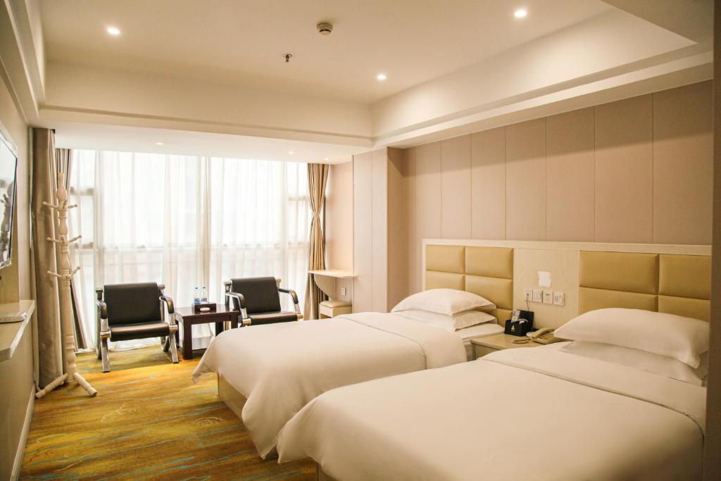 a hotel room with two beds and a table and chairs at Century Hotel Tongren in Tongren