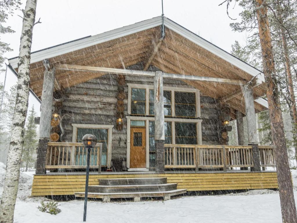 a log cabin with a porch in the snow at Holiday Home Kotkanpesä by Interhome in Levi