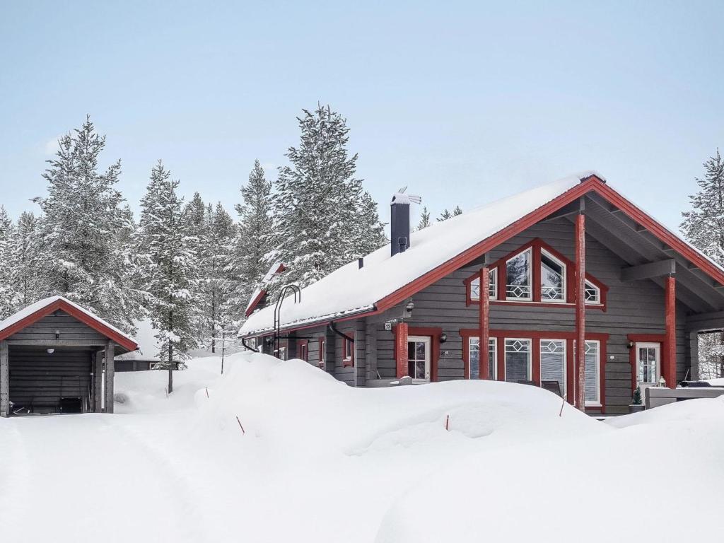 uma cabana de madeira coberta de neve com árvores ao fundo em Holiday Home Kerkänperä by Interhome em Luosto