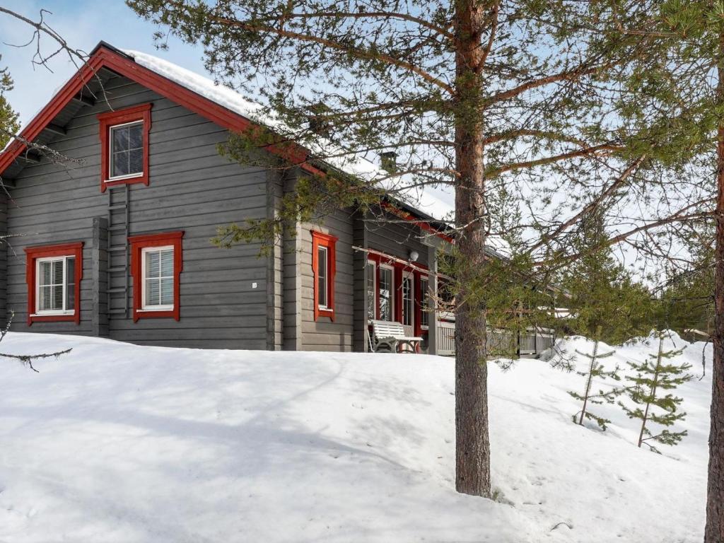 a gray house with red windows in the snow at Holiday Home Lustola b by Interhome in Luosto