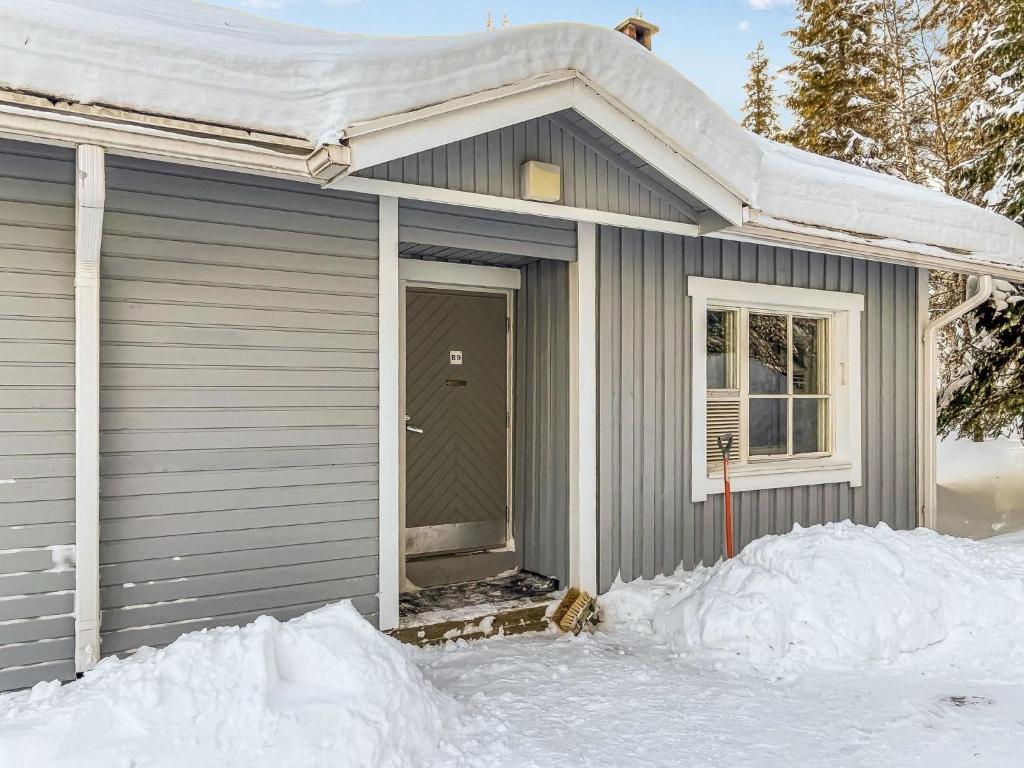 een grijs huis met een deur in de sneeuw bij Holiday Home Ylläskakkonen b9 by Interhome in Ylläsjärvi