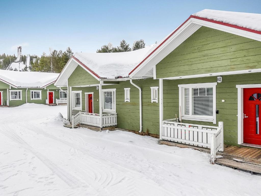 SaarenkyläにあるHoliday Home Huoneisto b2 by Interhomeの雪中の赤い扉が並ぶ緑の家