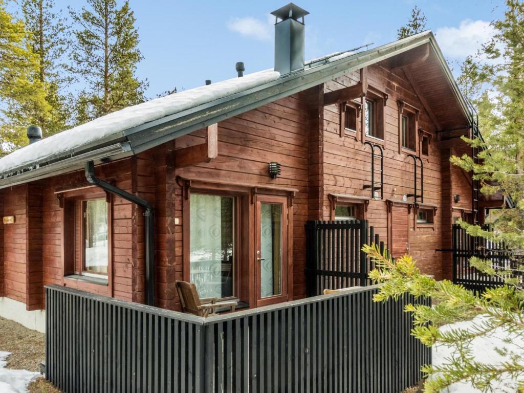 ein Holzhaus mit einem schwarzen Zaun davor in der Unterkunft Holiday Home Rovarakka 1 a by Interhome in Levi