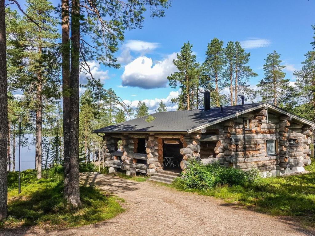 una baita di tronchi nel bosco con una strada sterrata di Holiday Home Villa mitja by Interhome a Karjalaisenniemi