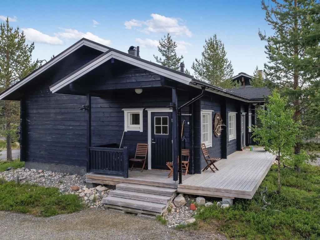 a small black cabin with a wooden deck at Holiday Home Tuulenpuuska by Interhome in Äkäslompolo