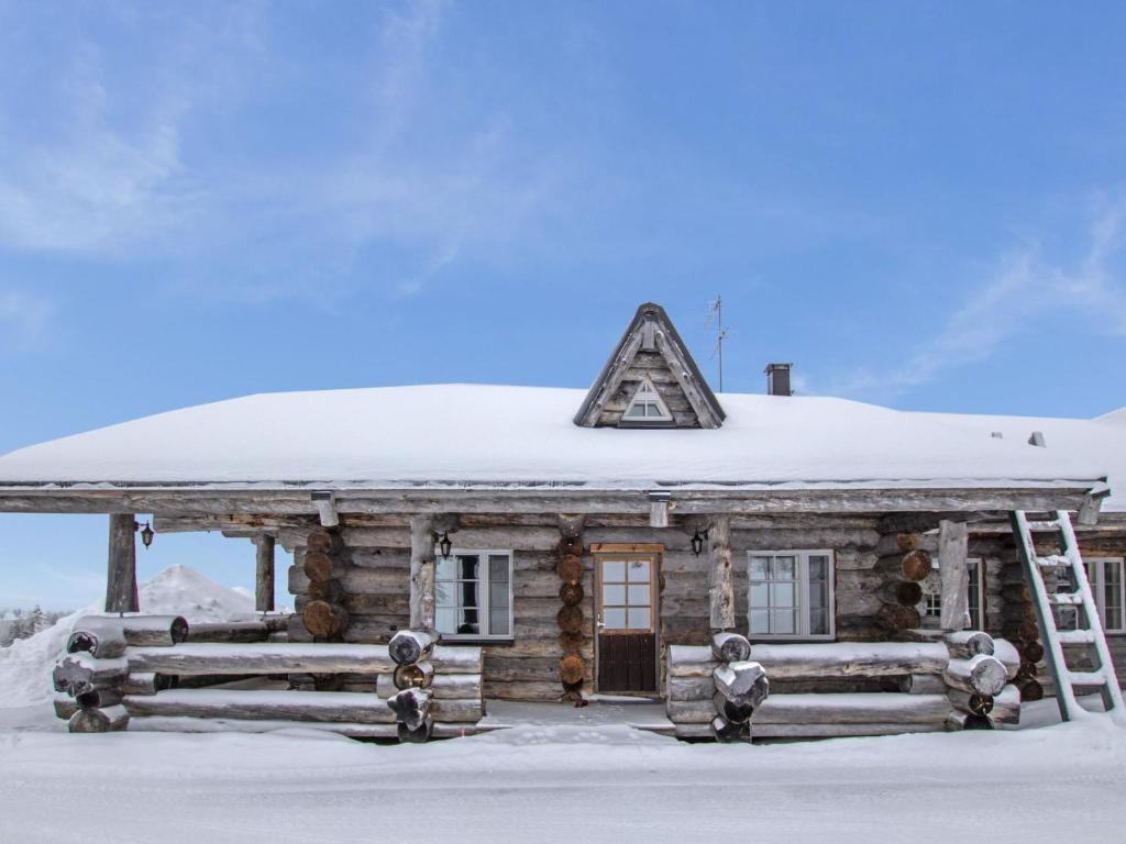 uma cabana de madeira com um telhado coberto de neve em Holiday Home Kaamosgammi by Interhome em Ylläs