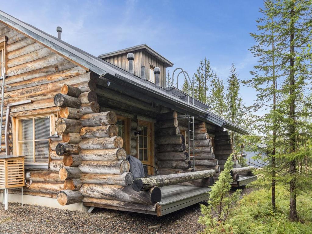 a log cabin with a porch and a large pile of logs at Holiday Home Kukasrakka c10 by Interhome in Äkäslompolo