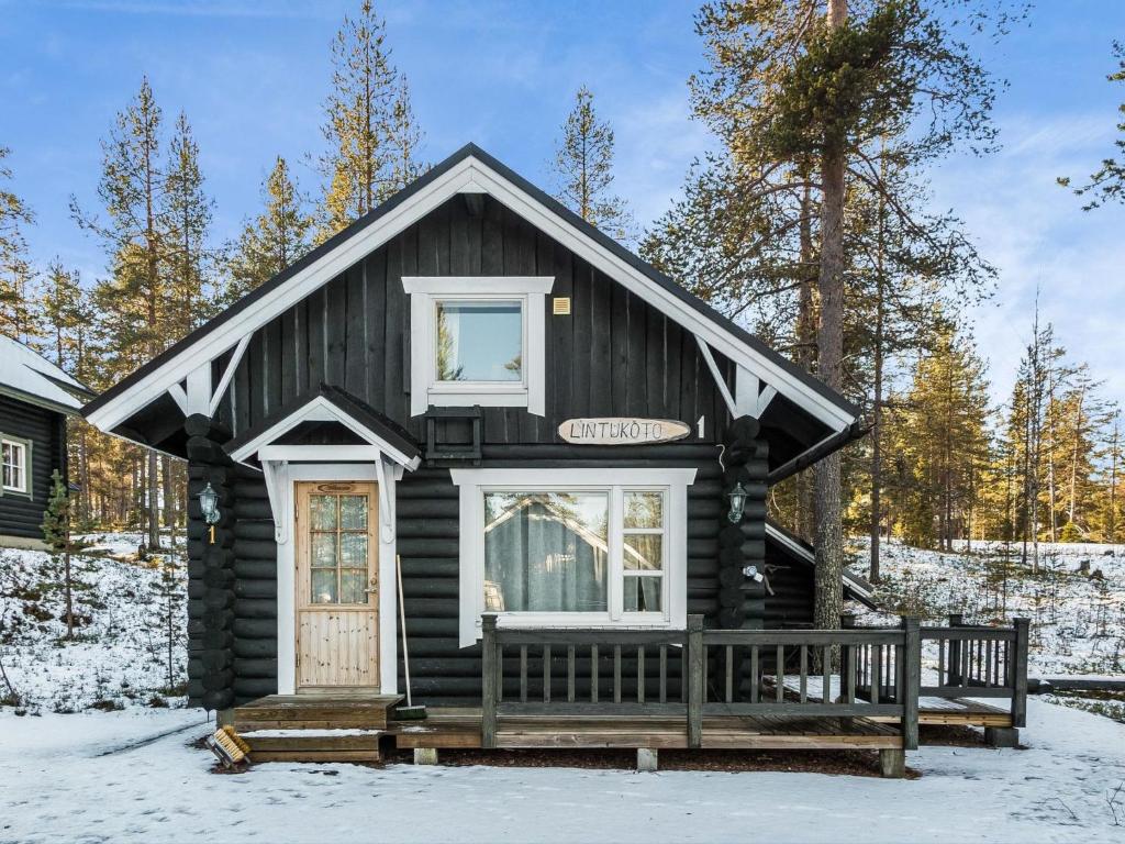 uma cabana de madeira com um alpendre na neve em Holiday Home Lintukoto by Interhome em Äkäslompolo