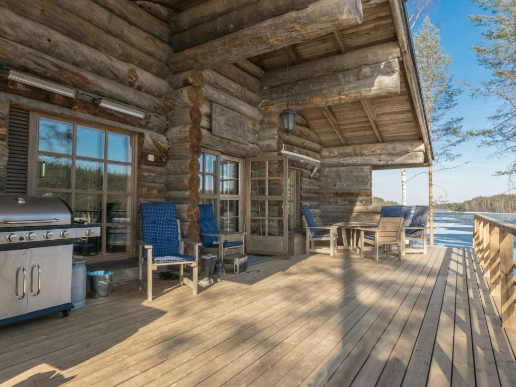 a log cabin with a grill and chairs on a deck at Holiday Home Villa moose by Interhome in Jukara