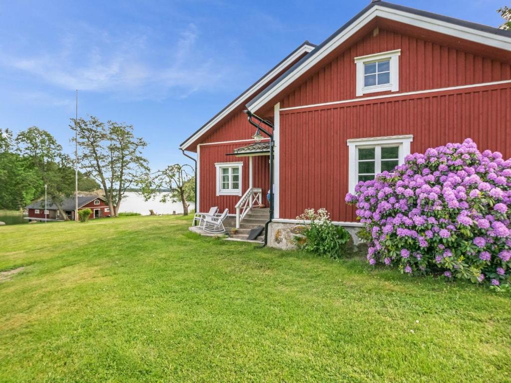 a red house with purple flowers in front of it at Holiday Home Villa nennebo by Interhome in Förby