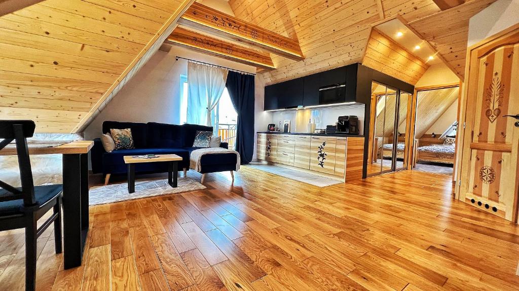 a living room with a blue couch and wooden ceilings at Apartament Podwika in Zakopane
