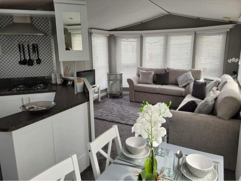 eine Küche und ein Wohnzimmer mit einem Tisch und einer Couch in der Unterkunft Palm Grove 28 - Golden Palm - Central heating, pet friendly, WiFi, bed linen - Meadow Lakes Caravan & Lodge Hire in Chapel Saint Leonards