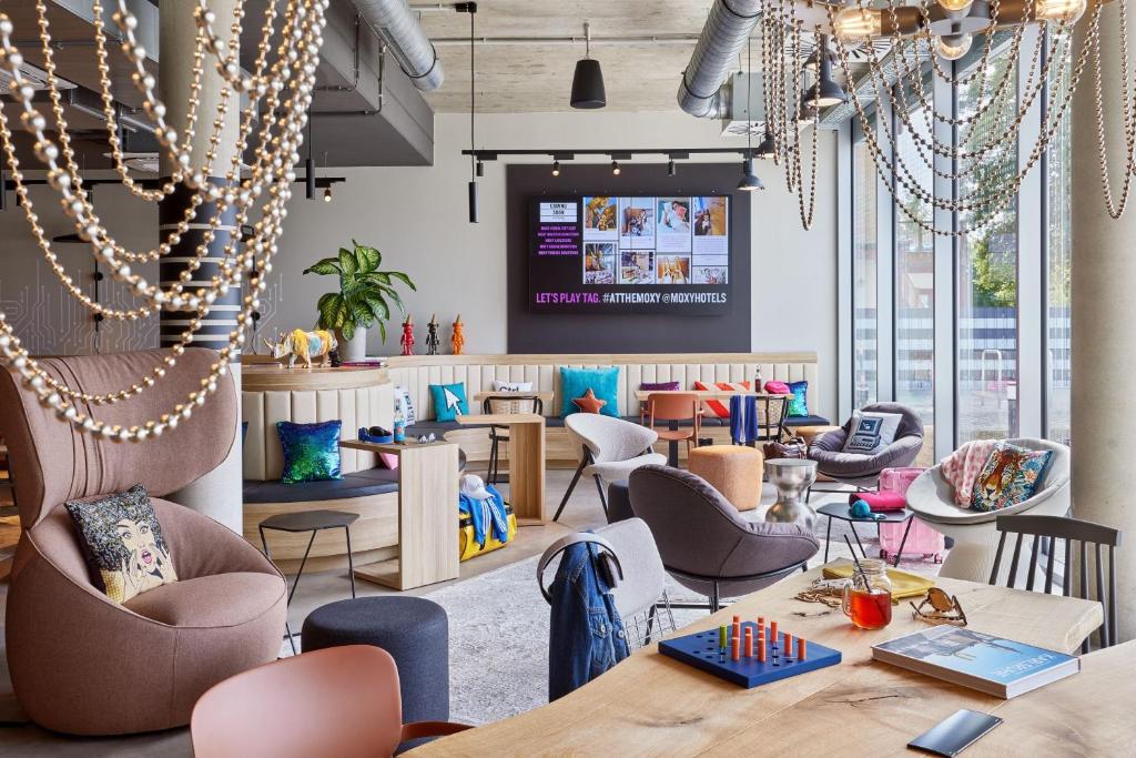 a restaurant with tables and chairs and a large window at Moxy Karlsruhe in Karlsruhe