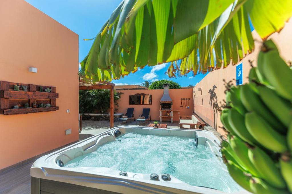 una bañera de hidromasaje en un patio trasero con un montón de plátanos en Villa Roby Corralejo en La Oliva