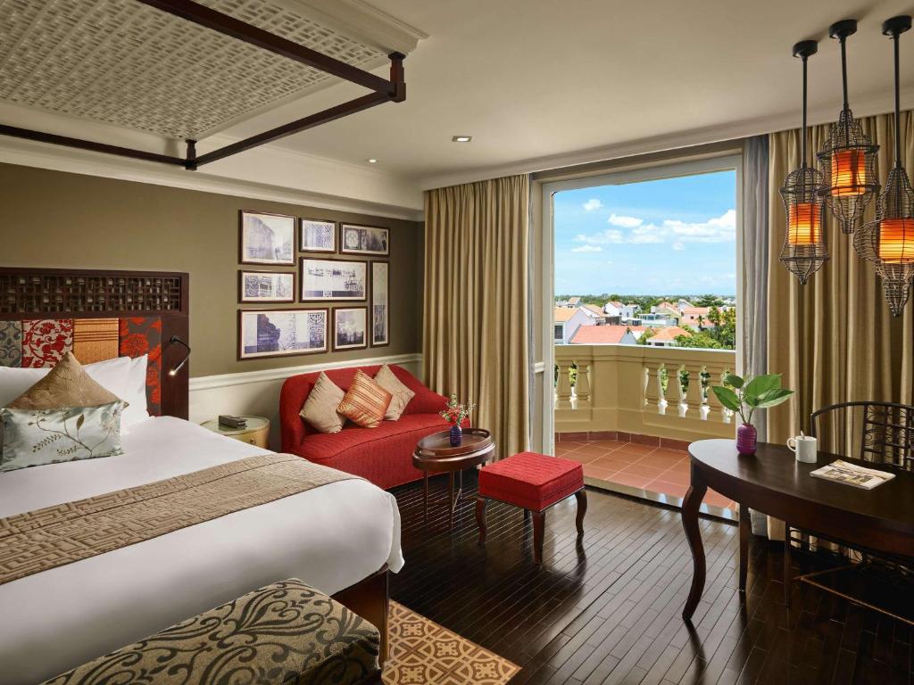 a hotel room with a bed and a large window at Hotel Royal Hoi An - MGallery in Hoi An