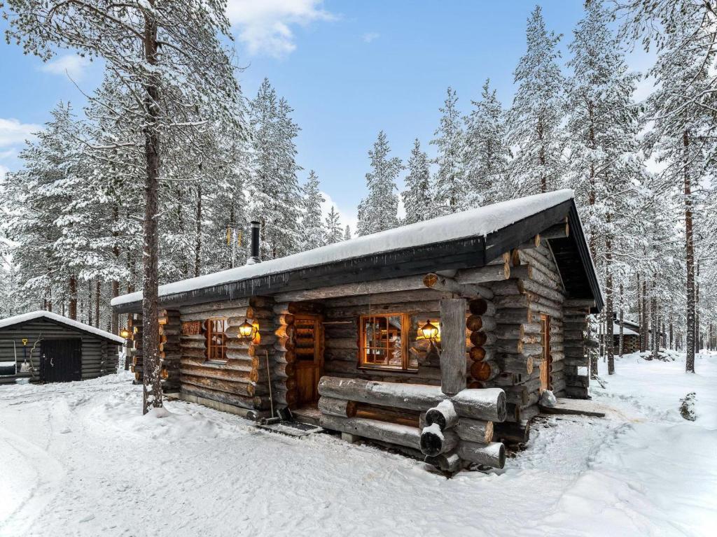 uma cabana de madeira na floresta na neve em Holiday Home Karkelo by Interhome em Ylläsjärvi