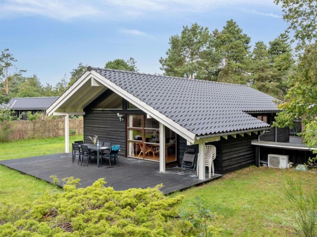 een hut met een terras met een tafel en stoelen bij Holiday Home Wilgrib - 400m from the sea in Sealand by Interhome in Højby