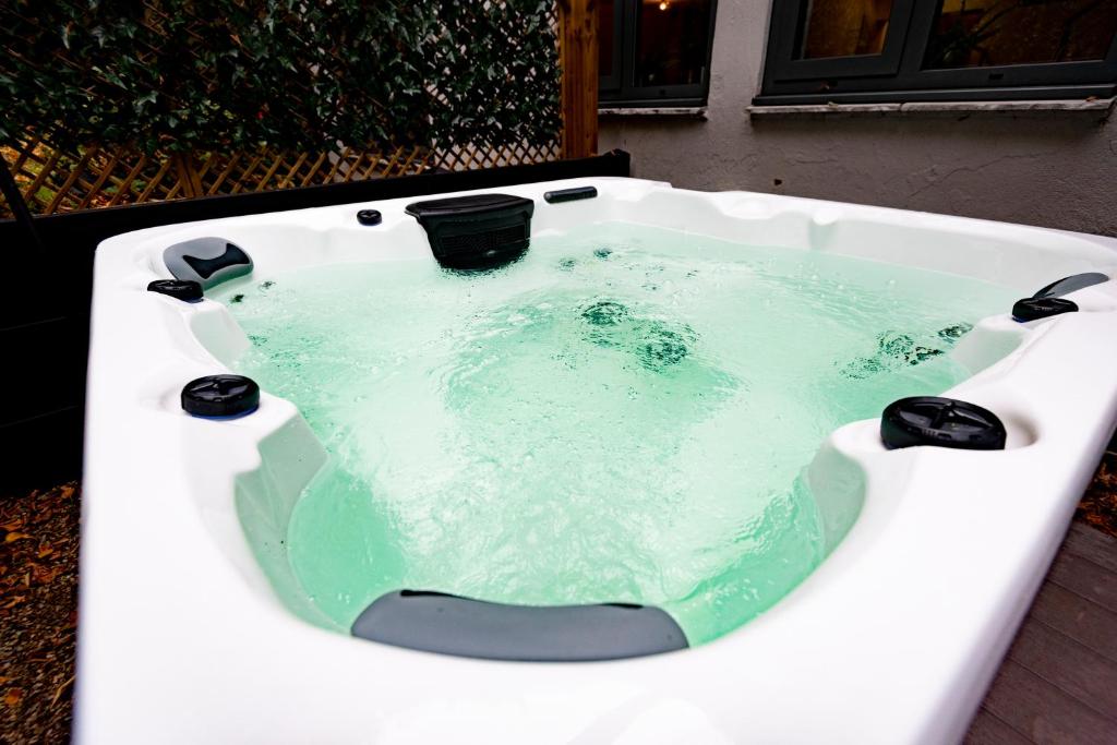 a white bath tub filled with green water at The Leeds Gathering - Hot Tub - EV Charging in Leeds