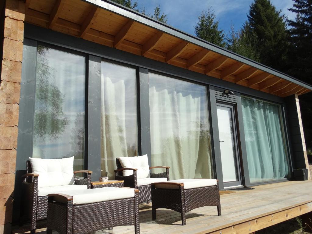 a screened in deck with chairs and windows at les lodges finlandais de la tortue permacole fine dentelle in Champclause
