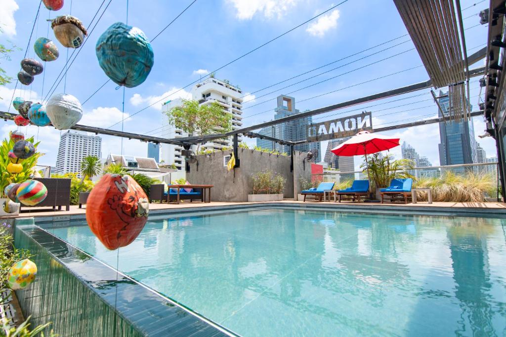 una piscina con pelotas de playa y sombrillas en un edificio en Galleria Sukhumvit 10 Bangkok by Compass Hospitality en Bangkok