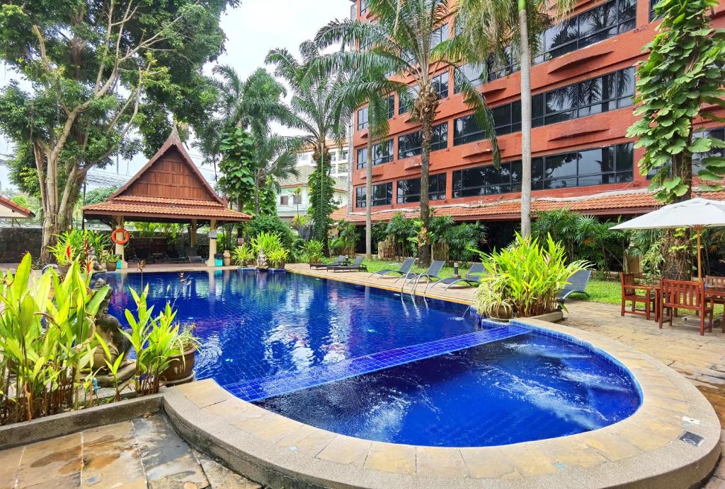 a swimming pool in front of a building at Nova Park Hotel Pattaya in Pattaya Central