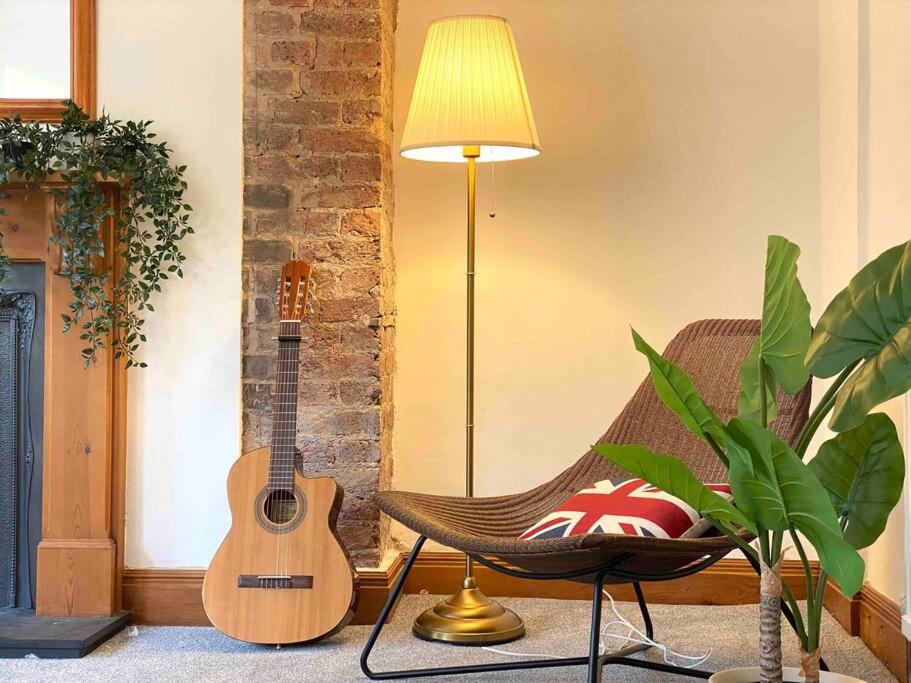 a guitar sitting next to a chair and a lamp at Vintage Apartment in King's Cross in London