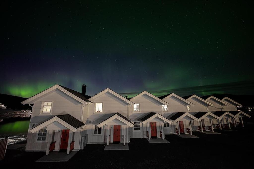 a row of houses under the green northern lights at Camp Aurora in Karlsøy