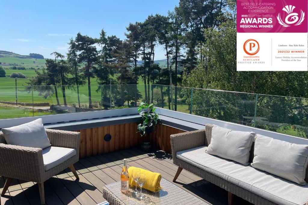 a balcony with two chairs and a couch and a table at Luxury Lodge with Hot Tub at Lindores in Newburgh