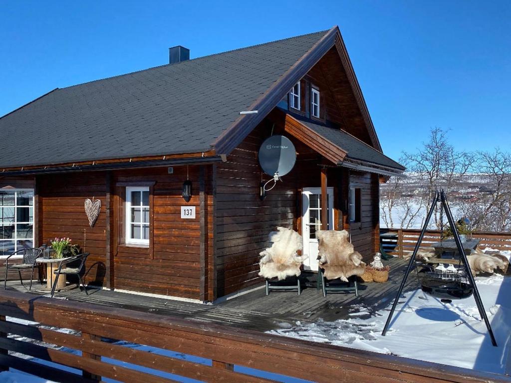 uma pequena cabana com cadeiras num deque na neve em Holiday Home Saanaloma by Interhome em Kilpisjärvi