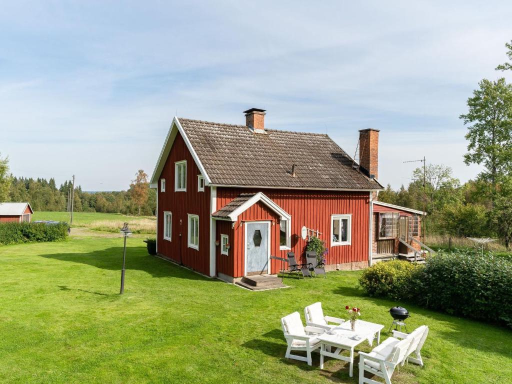 um celeiro vermelho com uma mesa e cadeiras em frente em Holiday Home Hultet - VGT098 by Interhome em Mullsjö