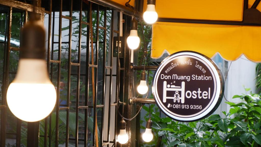 un cartello per un ristorante su un cancello con luci di DonMueang station hostel a Ban Don Muang (1)