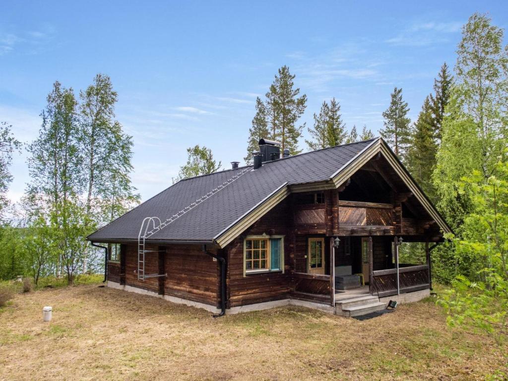 een blokhut met een zwart dak in het bos bij Holiday Home Kotimökki by Interhome in Sotkamo