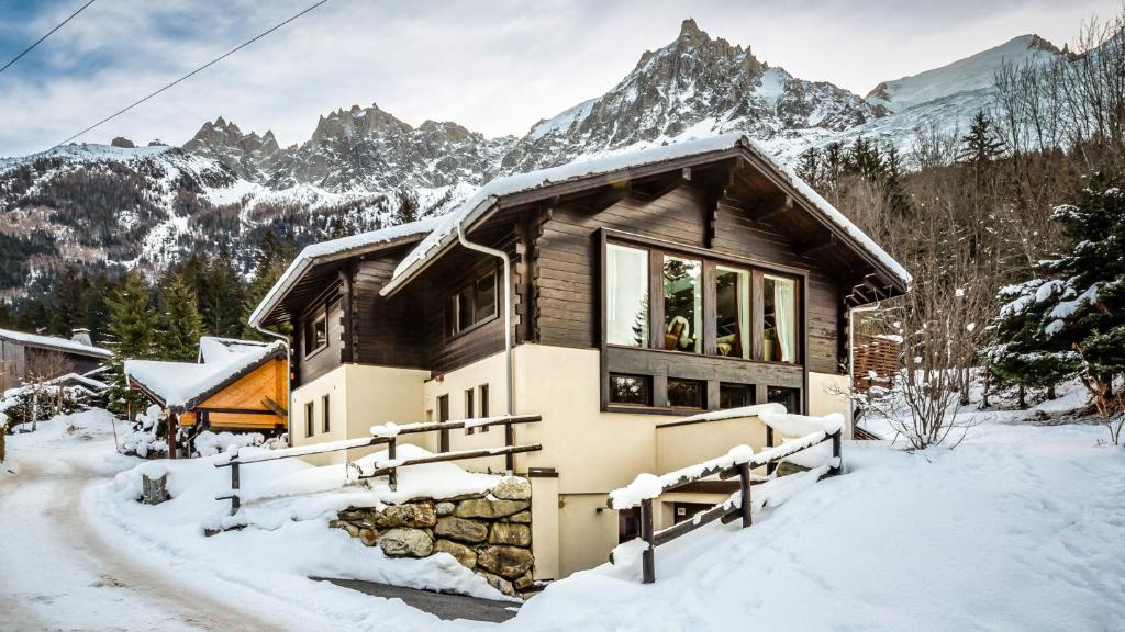 een huis in de sneeuw met bergen op de achtergrond bij Chalet Aubépines in Chamonix-Mont-Blanc