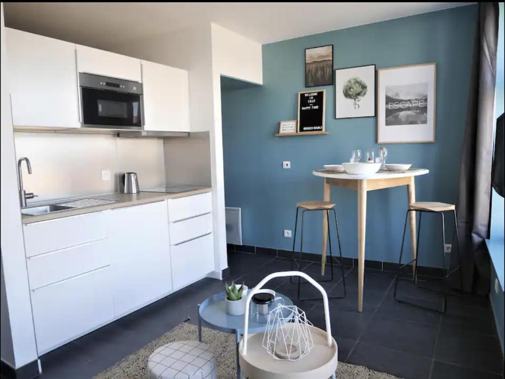 une cuisine avec des placards blancs et une table dans l'établissement Vieux-Lille - Studio en hypercentre, à Lille