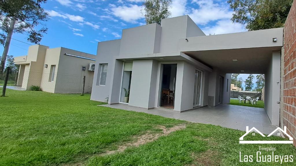 una casa blanca con césped delante en Las Gualeyas en Gualeguay