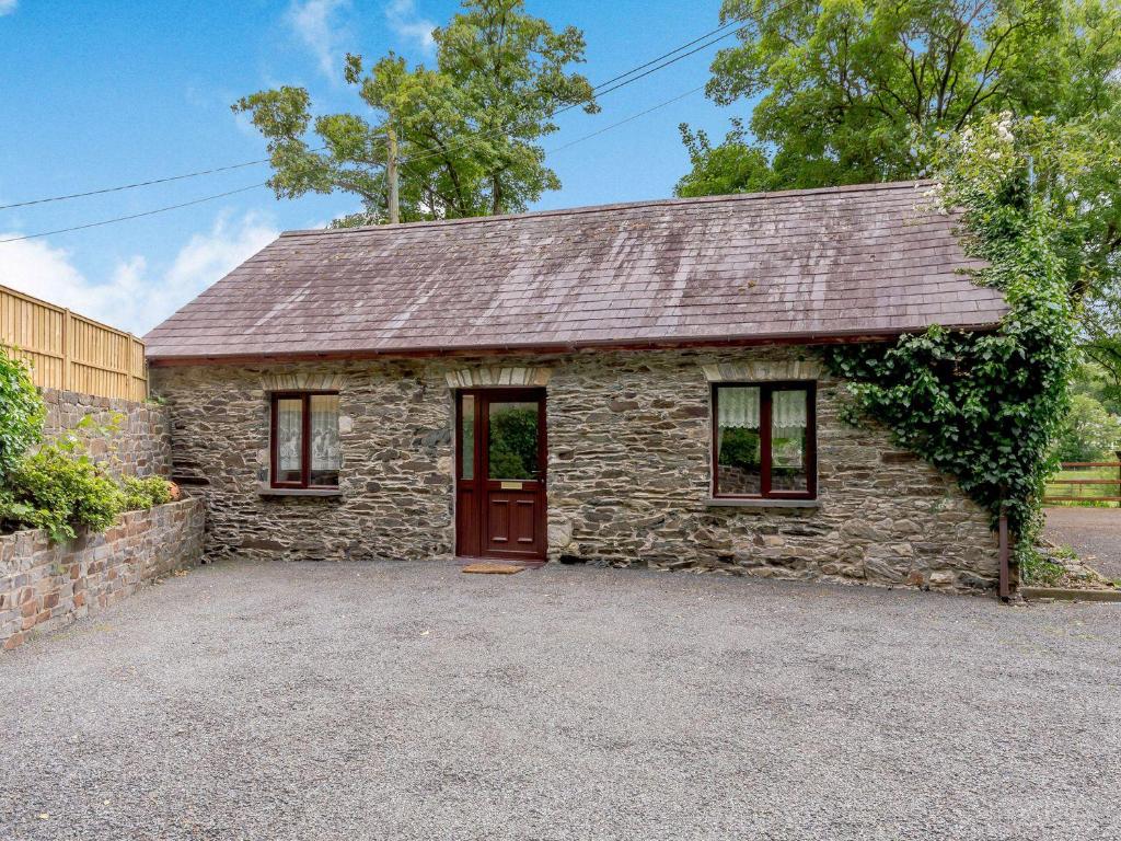 a stone house with a red door and windows at The Stable in Llandysul