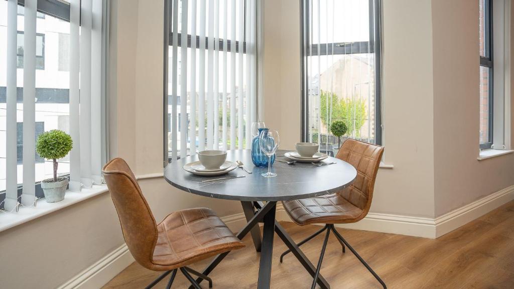 a table and chairs in a room with windows at Luxury 1 BDR City Apartments by Belfast City Breaks in Belfast