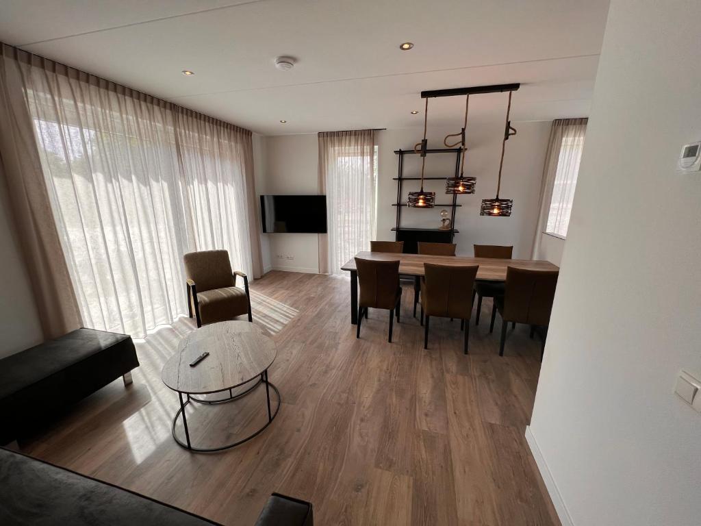 a living room with a table and a dining room at Luxe villa op Vakantiepark de Koorn-aar in Den Burg