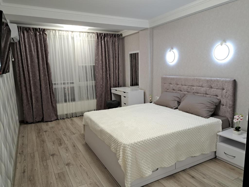 a bedroom with a white bed and two lights at Decebal in Chişinău