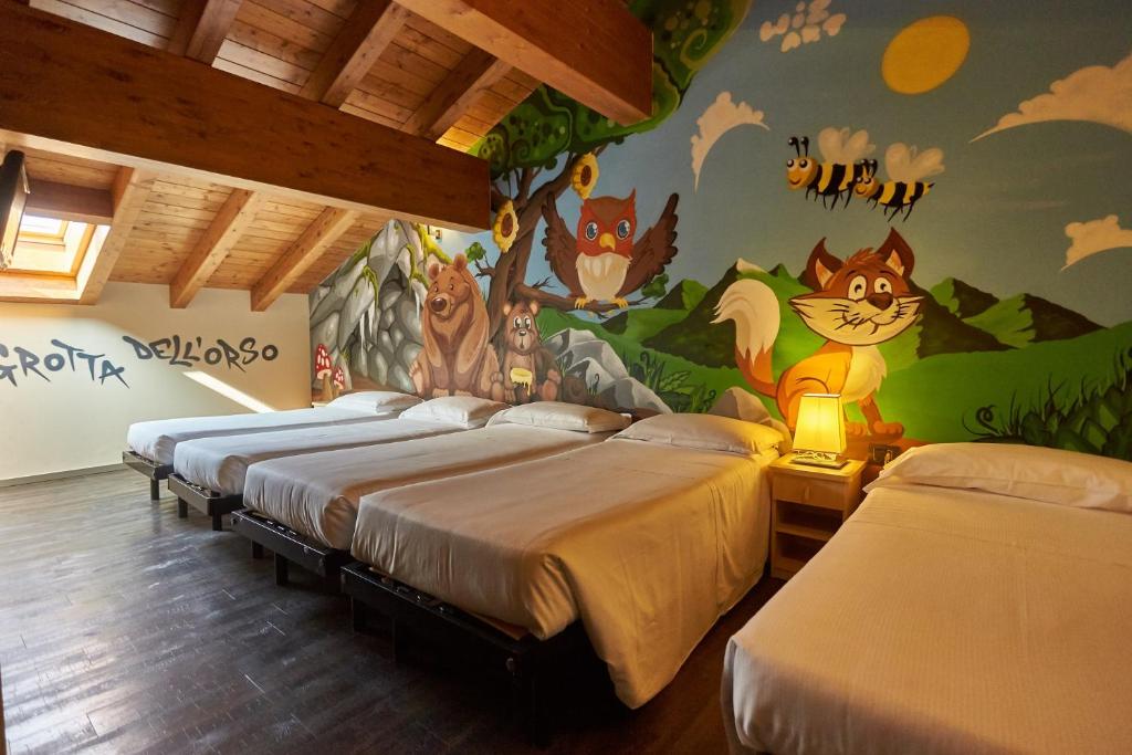 1 Schlafzimmer mit 4 Betten und einem Wandbild von Tieren in der Unterkunft Harmony Suite Hotel in Selvino